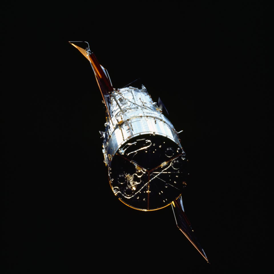 The Hubble Space Telescope, silver and gold against black space, photographed from Space Shuttle Endeavour before the 1993 repair mission